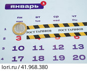 Лист отрывного календаря - январь месяц, десятирублевая монета и оградительная лента с надписью "рост тарифов" Стоковое фото, фотограф Цибаев Алексей / Фотобанк Лори