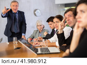 Outraged old manager getting mad at young adult mature office workers sitting with reports and laptops at table in meeting room. Стоковое фото, фотограф Яков Филимонов / Фотобанк Лори