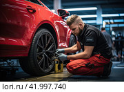 An auto mechanic repairs a car wheel at a service station. The concept of car maintenance. Стоковое AI-изображение, AI-художник Ярославский Максим / Фотобанк Лори