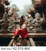 a woman in a red skirt is sitting in a boat with an airplane on the dock. Стоковое AI-изображение, AI-художник Юлия Гапеенко / Фотобанк Лори