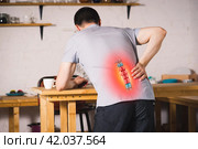 Pain in the spine, a man with backache at home, injury in the lower back. Стоковое фото, фотограф Станислав Тарко / Фотобанк Лори