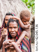 Wamena, Indonesia - January 9, 2010: People of the Dani tribe standing in Dugum Dani Village. Редакционное фото, фотограф VittoriaChe / Фотобанк Лори