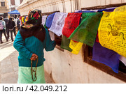 Kathmandu, Nepal - November 22, 2015: Old woman praying around the Boudhanath stupa and turning tibetan prayer wheels. Редакционное фото, фотограф VittoriaChe / Фотобанк Лори