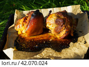Pork knuckle. Roasted pork knuckle baked in the oven on parchment paper. Large portions of food in nature. Close-up. Стоковое фото, фотограф Артем Лукин / Фотобанк Лори