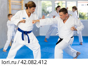 Man father is paired with coach to learn how to strike and rehearses blocking opponent. Стоковое фото, фотограф Яков Филимонов / Фотобанк Лори
