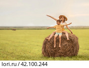 Девочка и мальчик сидят на стоге сена в поле и смеются. Стоковое фото, фотограф Анастасия Пипко / Фотобанк Лори