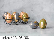 Stylish beautiful Easter eggs with golden potali coating on a gray background. The concept of happy Easter 2024. Стоковое фото, фотограф Photojuli / Фотобанк Лори
