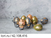 Stylish beautiful Easter eggs with golden potali coating on a gray background. The concept of happy Easter 2024. Стоковое фото, фотограф Photojuli / Фотобанк Лори