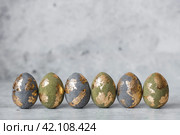Stylish beautiful Easter eggs with golden potali coating on a gray background. The concept of happy Easter 2024. Стоковое фото, фотограф Photojuli / Фотобанк Лори