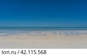 A paradisiacal minimalistic seascape. Sandy beach, aquamarine ocean, clear blue sky. Puddles and rivulets of water on the white sand. Madagascar. Nosy Iranja. Стоковое фото, фотограф Вера Ивановна Кубарева / Фотобанк Лори