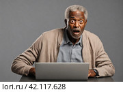Surprised senior man looking at laptop screen, isolated on grey background. Стоковое AI-изображение, AI-художник Васильева Юлия / Фотобанк Лори