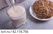 Pour the melted milk into a glass. Plate of cookies with cereals. Delicious healthy snack. Стоковое видео, видеограф Глущенко Елена / Фотобанк Лори