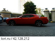 Красный гоночный автомобиль Додж Челленджер СРТ на парковке. Red Dodge Challenger SRT in the parking, side view. Summer sunset view. (2021 год). Редакционное фото, фотограф Александр Кузнецов / Фотобанк Лори