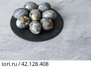 Stylish grey Easter eggs made of marble and concrete with a golden potala on a grey background. Coloring eggs with natural dye karkade tea. . The concept of a happy Easter. Стоковое фото, фотограф Photojuli / Фотобанк Лори