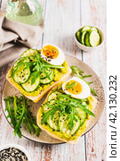 Bruschetta with guacomole, cucumber, egg and arugula on a plate vertical view. Стоковое фото, фотограф Елена Руй / Фотобанк Лори