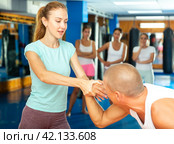 Young woman practicing supinating wristlock with man in self-defense course. Стоковое фото, фотограф Яков Филимонов / Фотобанк Лори