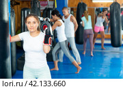 Young hispanic woman in boxing gloves practicing punches on punchbag. Стоковое фото, фотограф Яков Филимонов / Фотобанк Лори