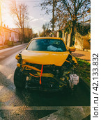 A yellow car wrecked in a car accident stands on a city street on a sunny autumn morning front view. Стоковое фото, фотограф Андрей С / Фотобанк Лори