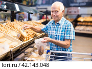 Old age senor examines bakery products in the grocery section of the supermarket. Стоковое фото, фотограф Татьяна Яцевич / Фотобанк Лори
