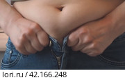 A woman with a fat belly tries to fasten her jeans. The concept of diet, excess weight or health. Стоковое видео, видеограф Глущенко Елена / Фотобанк Лори