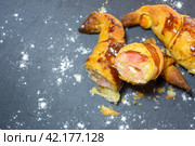 Sliced baked pastry with ham and cheese on a dark background, dusted with a powdery substance, homemade croissant stuffed and cut in half. Стоковое фото, фотограф carlos l vives / Фотобанк Лори