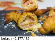 A close-up of a flaky, golden-brown pastry with ham and cheese filling, delicious and tasty puff pastry with ham and cheese. Стоковое фото, фотограф carlos l vives / Фотобанк Лори