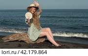 Smiling young woman holds mirror in her hand and closes herself with other hand from sun's rays. Стоковое видео, видеограф А. А. Пирагис / Фотобанк Лори