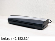 Black lamination device on a wooden table. Стоковое фото, фотограф Аксенова Вера / Фотобанк Лори