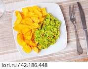 Beer snacks are laid out on plate - chips and portion of thick pasta sauce guacamole. Стоковое фото, фотограф Яков Филимонов / Фотобанк Лори