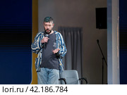 Confident male speaker with microphone at a casual event, engaging audience (2024 год). Редакционное фото, фотограф Антон Гвоздиков / Фотобанк Лори
