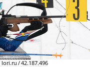 Sportswoman biathlete rifle shooting in prone position. Selective focus, extreme close-up. Biathlete in shooting range (2019 год). Редакционное фото, фотограф А. А. Пирагис / Фотобанк Лори