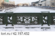 SAINT PETERSBURG, RUSSIA - January 17, 2024: View of the snow-covered Fontanka River from the famous Anichkov Bridge, decorated with a cast iron fence with seahorses on a sunny winter day. Редакционное фото, фотограф Виктория Катьянова / Фотобанк Лори