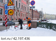 SAINT PETERSBURG, RUSSIA - January 17, 2024: City utility workers clear ice and snow from sidewalks along Fontanka River embankment near Beloselsky-Belozersky Palace on snowy winter day. Редакционное фото, фотограф Виктория Катьянова / Фотобанк Лори