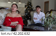 Disappointed young couple arguing among themselves before Christmas Eve while sitting on sofa in living room at home. Стоковое видео, видеограф Яков Филимонов / Фотобанк Лори