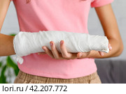Close-up of a hand with a fracture in a cast. The concept of an accident insured event. Selective focus on bandage with plaster. Стоковое фото, фотограф Никита Бурденков / Фотобанк Лори