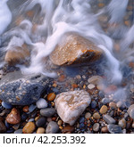 Rocks and pebbles are softly caressed by the ebbing and flowing tide. Стоковое AI-изображение, AI-художник Юлия Гапеенко / Фотобанк Лори