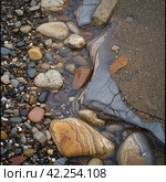 Rocks and pebbles are softly caressed by the ebbing and flowing tide. Стоковое AI-изображение, AI-художник Юлия Гапеенко / Фотобанк Лори