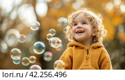A toddler's giggle as they pop soap bubbles, the epitome of simple childhood joys. Стоковое AI-изображение, AI-художник Юлия Гапеенко / Фотобанк Лори