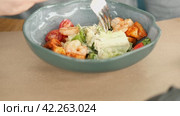 Unrecognized Male Person Eat Caesar Salad with Shrimps, Lettuce, Tomatoes, Croutons. Young Man Eating Fresh Vegetable Delicious Side Dish in a Restaurant. Business Lunch. Healthy food. Vegetarian food. Стоковое видео, видеограф Марина Демидюк / Фотобанк Лори
