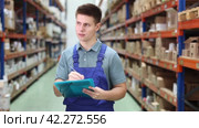 In warehouse of store, guy checks quantity of goods and receipt documents for products. Стоковое видео, видеограф Яков Филимонов / Фотобанк Лори