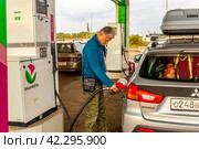 Russia Samara. September 15, 2023: elderly man tourist refueling his car for traveling around his home country. text in Russian: Bashneft. Редакционное фото, фотограф Акиньшин Владимир / Фотобанк Лори