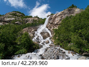 View of the Alibek waterfall formed by the fall of the Jalovchatka River from the Alibek glacier on a sunny summer day, Dombay, Karachay-Cherkessia, Russia. Стоковое фото, фотограф Ula Ulachka / Фотобанк Лори