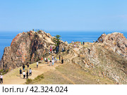 BAIKAL LAKE, UZURY VILLAGE, OLKHON ISLAND, IRKUTSK REGION, RUSSIA - August 15, 2023: Groups of tourists come to famous rocky cape Shunte Left or Cape of Love to take pictures of scenic landscape. Редакционное фото, фотограф Виктория Катьянова / Фотобанк Лори