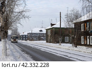 Улица в сибирском городе. Вид на многоквартирные деревянные дома. По проезжей части едет автобус. Повседневная жизнь в Сибири. Город Братск, Иркутская область, Россия. Восточная Сибирь. Холодная зимняя погода. Стоковое фото, фотограф Андрей Степанов / Фотобанк Лори