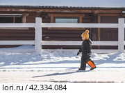 Portrait of a little boy in a yellow hat. The child runs through puddles on the farm, has fun and plays. It's a sunny day. Early spring. The first drop. Стоковое фото, фотограф Photojuli / Фотобанк Лори