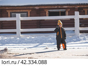 Portrait of a little boy in a yellow hat. The child runs through puddles on the farm, has fun and plays. It's a sunny day. Early spring. The first drop. Стоковое фото, фотограф Photojuli / Фотобанк Лори