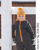 Portrait of a little boy in a yellow hat. The child runs through puddles on the farm, has fun and plays. It's a sunny day. Early spring. The first drop. Стоковое фото, фотограф Photojuli / Фотобанк Лори