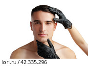 Cosmetician hands in protective gloves touching face of young handsome man. Стоковое фото, фотограф Сергей Толмачёв / Фотобанк Лори