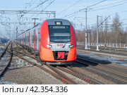 Скоростной электропоезд "ЭС2Г-144 "Ласточка" прибывает на станцию Славянка солнечным мартовским днем. Октябрьская железная дорога (2024 год). Редакционное фото, фотограф Виктор Карасев / Фотобанк Лори