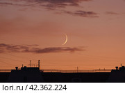 Photography of the roofs of houses and growing moon over Moscow in the sunset. Lifestyles concepts. The city is shrouded in electromagnetic waves of different lengths. Concepts of danger for health. (2019 год). Стоковое фото, фотограф YuryKara / Фотобанк Лори